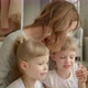Mom with Daughters Behind a Laptop and Kisses Them - VideoHive Item for Sale