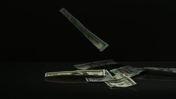 American $100 Bills Falling onto a Reflective Surface