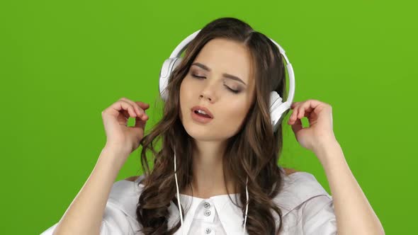 Girl Enjoys Music Through Headphones and Sing Along. Green Screen. Close Up