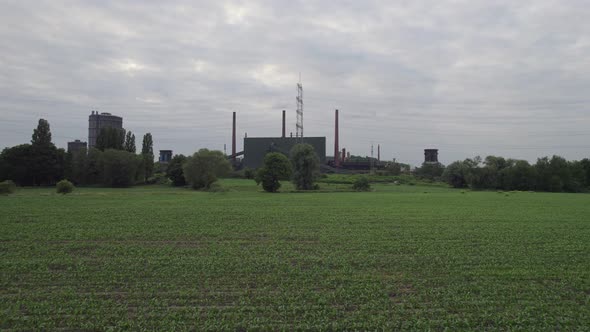 Juxtaposition of agricultural land and industry, aerial drone crane shot, overcast day