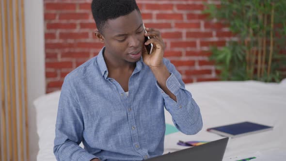 Young Confident Man Discussing Business Idea on the Phone Sitting in Comfortable Bedroom Indoors