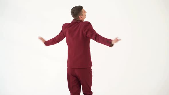 fun showman in red suit is waving his arms and spinning around himself on a white background