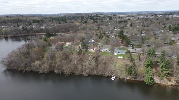 Aerial view over small rural community from lake in autumn. Ripples in the water.