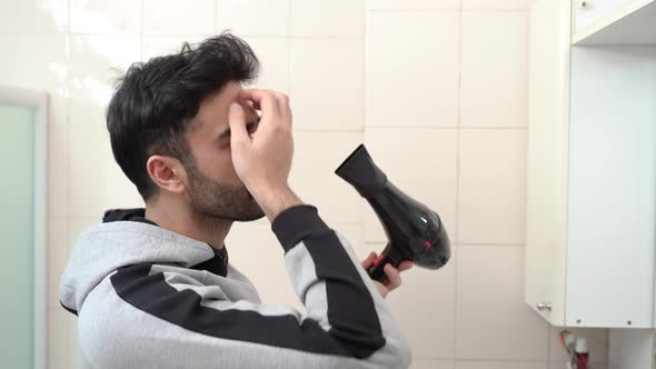 Handsome man using hair dryer.