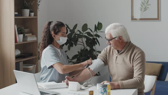 Female Doctor Taking Blood Pressure of Senior Patient