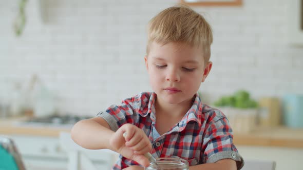 Cute blond toddler boy eating snacks with milk and watching cartoons on tablet