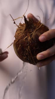 Female Hands Open the Coconut Coconut Water Pours Out