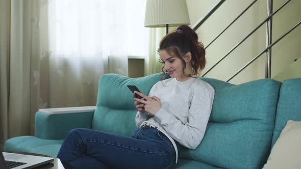 Relaxed Young Woman Using Smart Phone Surfing Social Media, Checking News, Playing Mobile Games