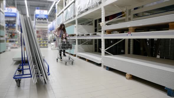 Cute Child Sitting in Grocery Cart, While Her Mother Is Pushing the Cart Forward Riding on It