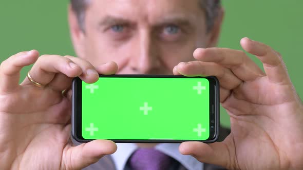 Mature Handsome Businessman Against Green Background