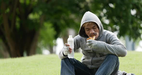 Homeless man drinking and eating food