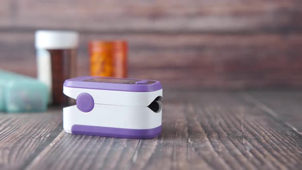 Pulse Oximeter and Medical Pills on Wooden Table