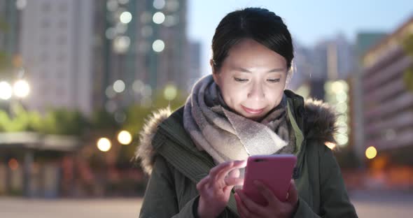 Woman use of smart phone at outdoor in winter time at night