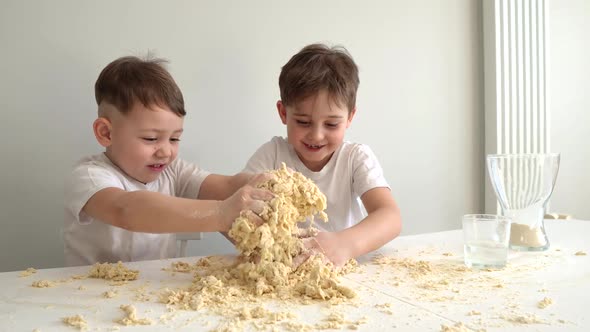 Two Little Brothers Knead Dough in the Kitchen