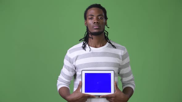 Young Handsome African Man with Dreadlocks Against Green Background