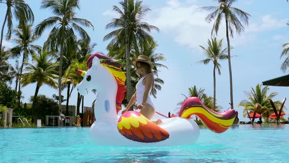 Vacation Woman on Inflatable Unicorn Float Mattress Having Fun in Swimming Pool