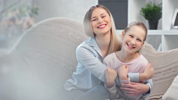 Adorable Smiling Young Mother Hugging Cute Daughter Posing Together Surrounded By Light Glare