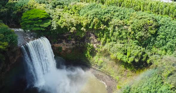 Drone shot above a waterfall and rainbow in Kauai.