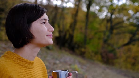 Pretty Young Woman with Hot Tasty Drink Spending Vacations Among Autumn Forest