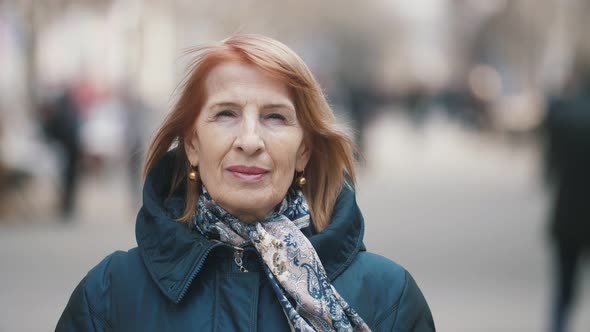 Bright Senior Lady in Elegant Scarf Standing in Airy Alley in Autumn in Slo-mo   