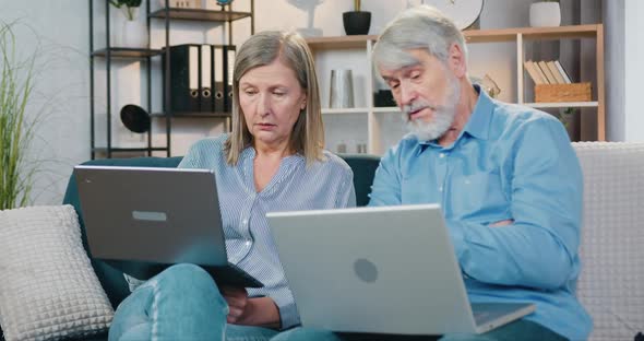 Retired Man and Woman Sitting on Couch and Using Laptops