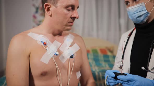 Doctor Checks Holter Heart Monitor at Patient's Home