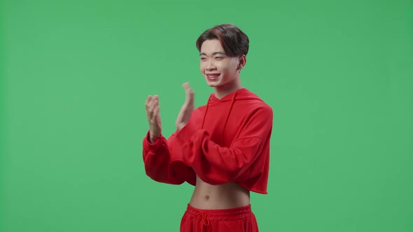 Side View Of Young Asian Transgender Male Clapping Her Hands In The Green Screen Studio