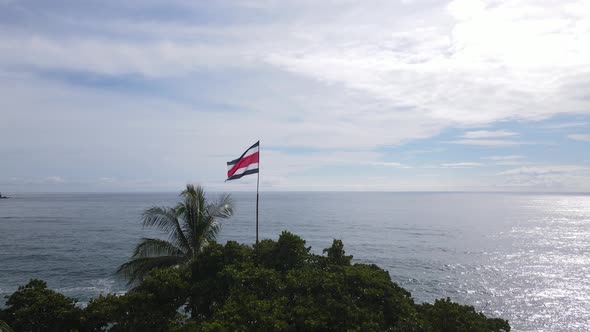 The flag of Costa Rica sits upon a mountain with a view of the sea behind