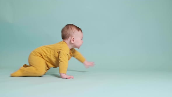 Happy toddler baby plays at the age of six months laughing on studio blue background