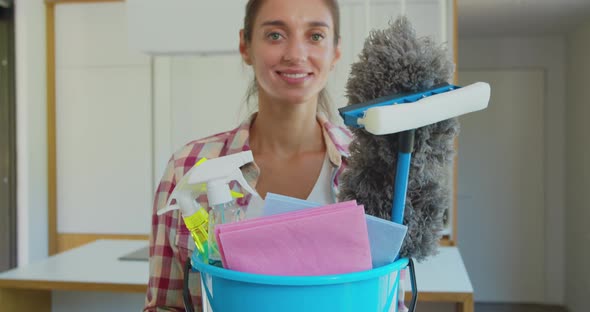 Cleaning Concept. Young Woman Holds Basin with Washing Fluids and Rags in Hands.