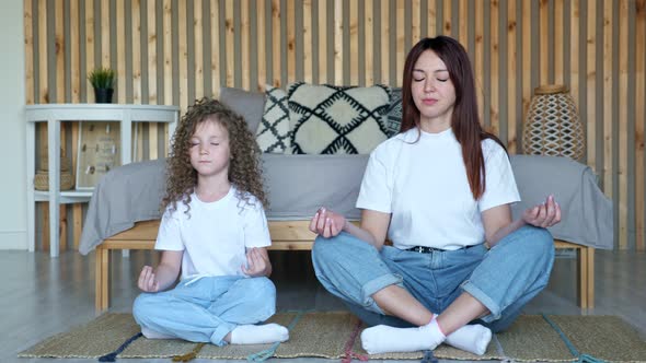 Little Girl with Loose Hair and Mother Sit in Yoga Poses