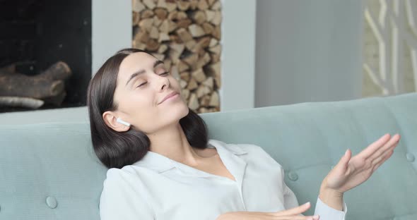 Young Woman Relaxing on Comfortable Couch Enjoying Listening to Lounge Music Live Via Smartphone App