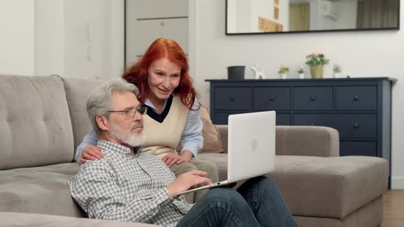 Senior Couple in Their 60s and 70s Make an Online Purchase of a House Using a Laptop