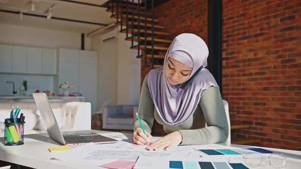 Girl in an Islamic Headscarf Works at Home with a Laptop and a Phone