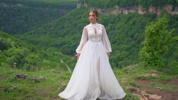 A Beautiful Woman in a Wedding Dress and Black Boots Posing in the Mountains