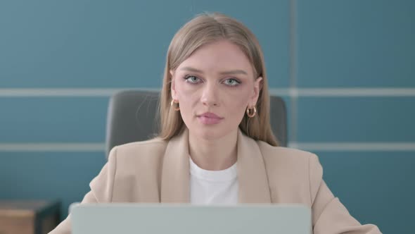 Close Up of Businesswoman Smiling at Camera While Using Laptop in Office