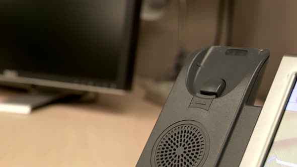 A close up of a hand slamming an office phone down onto the phone receiver in slow motion.