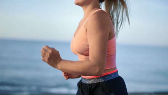 Closeup Torso of Muscular Female Athlete Running on Beach