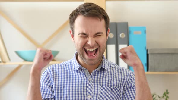 Winning Man Sitting in Office Celebrating Success