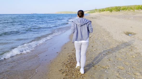 Girl in Tracksuit Runs Along the Coast