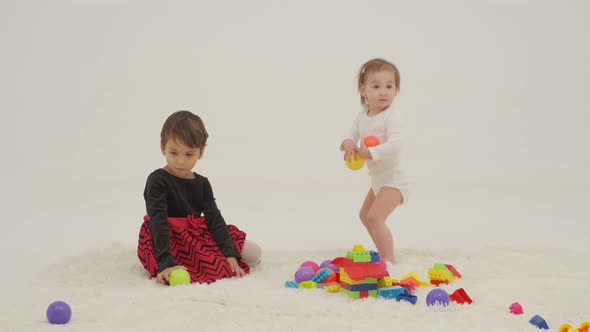 Toddler Girl Wearing Diaper and Her Sister Playing with Balls