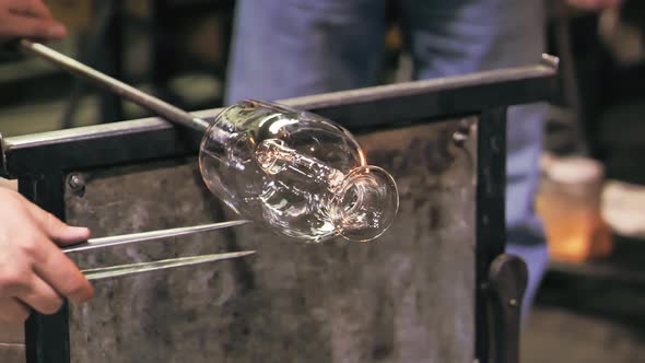 Glass artist shaping vase handle. Static, slomo