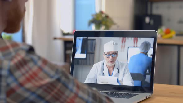 Man Having Video Call with Doctor on Laptop at Home Online Consultation Concept
