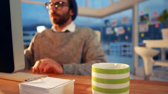 Business executive working on computer while having coffee