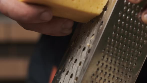 Close Up Macro Male Hands Chef Rubs Cheese on Iron Grater