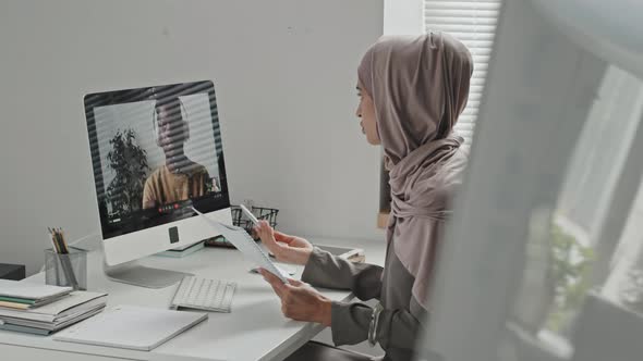 Muslim Woman Talking on Video Call with Coworker in Office