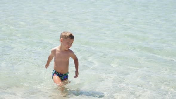 Tanned Boy Bathed in the Sea and Goes to the Shore