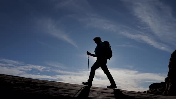 Silhouette Of Hiker With A Backpack Hiking Uphill On Background Of Sunset Rays