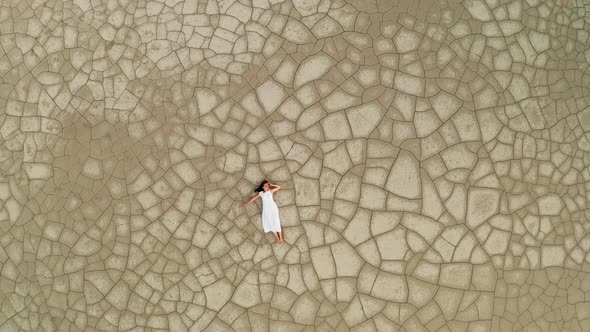 Aerial View of a Woman Lying on the Cracked Ground