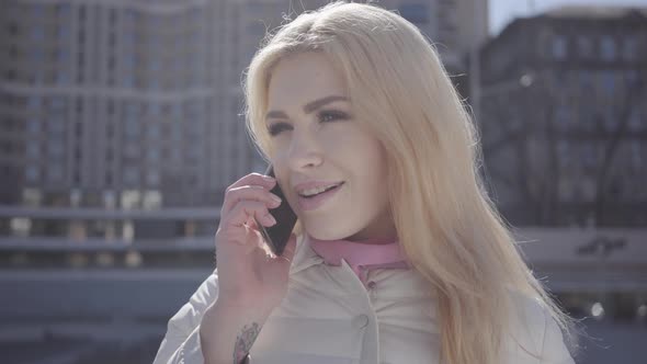 Portrait of Blond Woman with Teeth Braces in Warm Coat Standing in the City Street